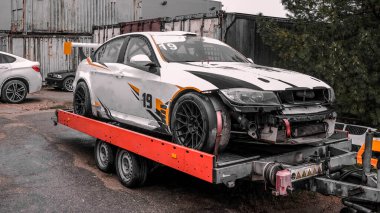 Sokakta bir karavanda kaza yapmış beyaz bir spor arabanın fotoğrafı..