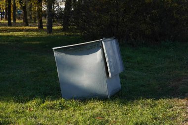 Ormandaki yeşil çimlerin üzerinde gri bir çöp tenekesinin fotoğrafı..