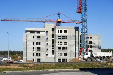 Turnaların ve inşaat makinelerinin yanına gri bir ev inşa etme süreci.