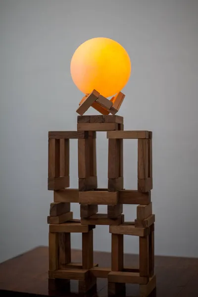 Kahverengi tahta bloklarda parlayan sarı bir topun fotoğrafı..