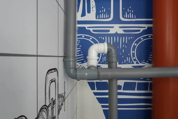 Bir deniz temasının mavi duvarının arka planında gri ve beyaz boruların fotoğrafı.