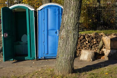 Parktaki sokakta mavi ve yeşil gübre tuvaletlerinin fotoğrafı..