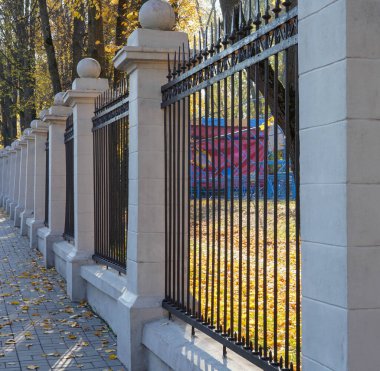 Şehirdeki bir parkın yakınındaki siyah metal çitin dikey fotoğrafı..