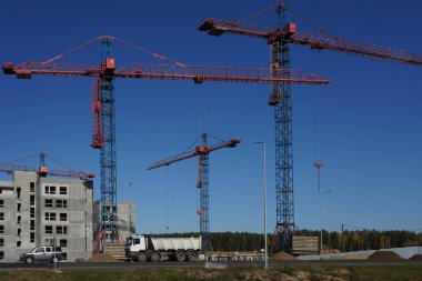 Turnaların ve inşaat malzemelerinin yanına gri bir ev inşa etme süreci.