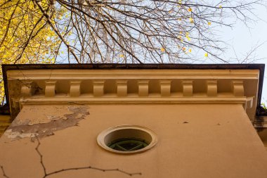 Gökyüzüne karşı sarı eski bir evin çatısı ve şehirdeki ağaçların fotoğrafı..