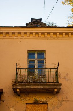 Şehirdeki sarı bir evin eski, açık bir balkonunun dikey fotoğrafı..