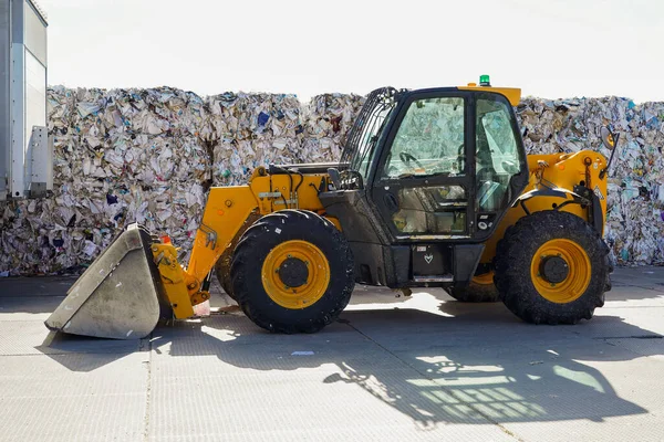 Çöplüğün arka planında sarı bir traktörün fotoğrafı..