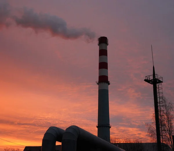 Güzel renkli gökyüzünün arka planında dumanın çok yoğun olduğu büyük baca..