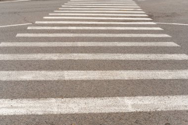 Şehirdeki insanlar için beyaz çizgili gri bir asfalt üzerinde yaya geçidi fotoğrafı..