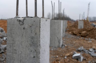 İnşaat metal çubuklarının beton sütunlardaki fotoğrafı sokaktaki bir inşaat alanının arka planına karşı..