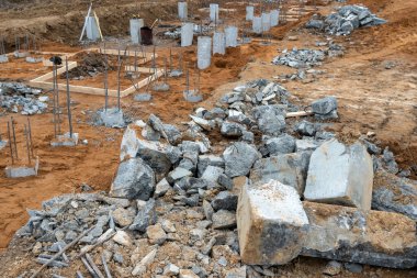 İnşaat metal çubuklarının beton sütunlardaki fotoğrafı sokaktaki bir inşaat alanının arka planına karşı..