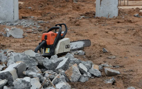 Beton sütunlarda bulunan testere ve inşaat metal çubuklarının fotoğrafı sokaktaki bir inşaat alanının arka planına karşı..
