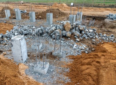 İnşaat metal çubuklarının beton sütunlardaki fotoğrafı sokaktaki bir inşaat alanının arka planına karşı..