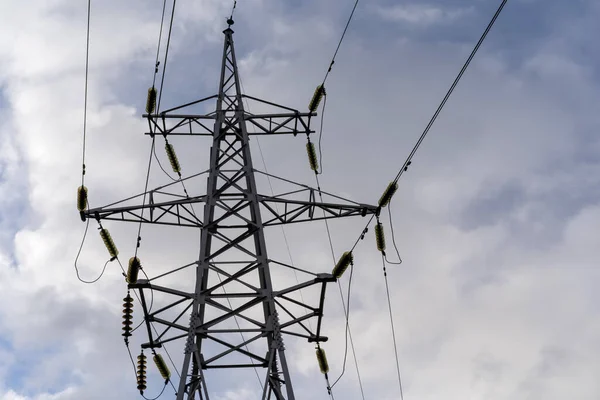 Beyaz bulutlu mavi gökyüzü üzerinde elektrik kabloları olan kutupların fotoğrafı.