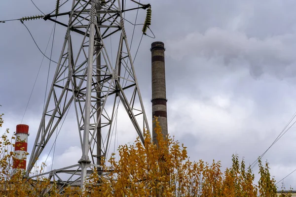Gökyüzünün arka planında beyaz ve kırmızı boruların ve elektrik kablolarının bulutlu koyu renkli fotoğrafı. Çalışan buharlı boru, ısıtıcı..