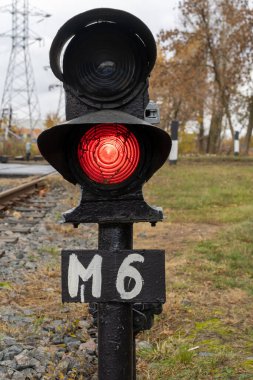 Demiryolunun arkasındaki trafik lambasında yanan kırmızı ışığın dikey fotoğrafı. Tren konsepti.