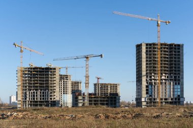 Şehirdeki inşaat alanının ve yüksek bina ve vinçlerin fotoğrafı.