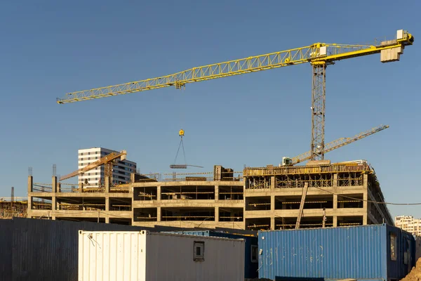 Şehirdeki mavi gökyüzüne karşı inşaat alanının ve yüksek binaların ve vinçlerin fotoğrafı. Yapısal kavram.