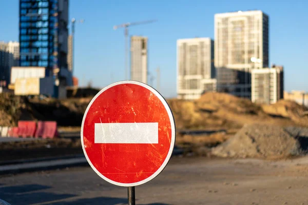 İnşaat alanının fotoğrafı, yüksek binalar ve vinçler. Kırmızı ve beyaz daire dur tabelası. Yapısal kavram.