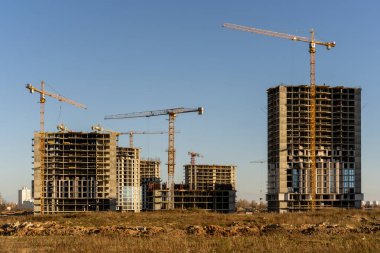 Şehirdeki inşaat alanının ve yüksek bina ve vinçlerin fotoğrafı.