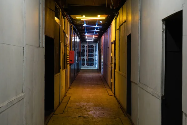 Kapısı ve duvarları renkli lambaları olan uzun bir atmosferik koridorun fotoğrafı..