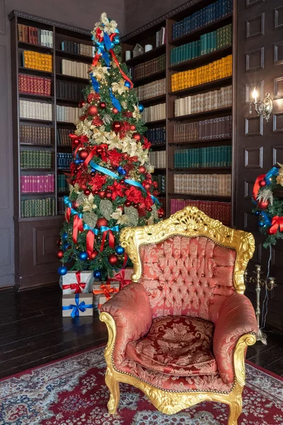 Dikey fotoğraf ve koltuk ve yeşil bir noel ağacı topları, yayları ve kutuları ile kitaplık arka planında hediyeler. Yeni yıl ve tatil.
