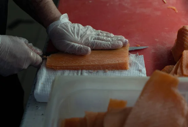 Bir Japon restoranının şefi büyük bir kırmızı balığı keskin bir bıçakla keser.