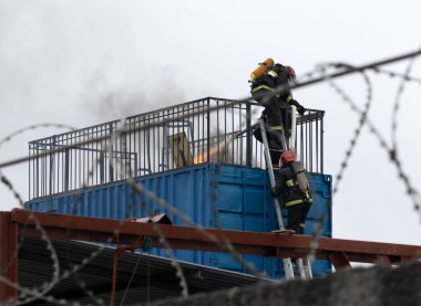 İtfaiyeciler bir depodaki yangını suyla söndürüyor.