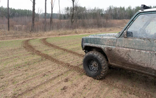 Kirli bir arabanın ve yerdeki derin tekerlek izinin fotoğrafı..