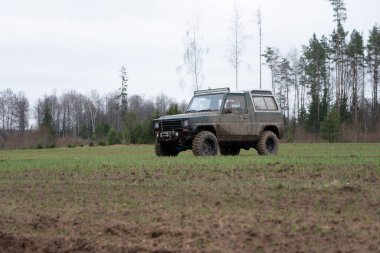 Bir 4x4 SUV aracı off-road arazisinde ve ıslak toprak yolda. Ulaşım ve spor macera konsepti.