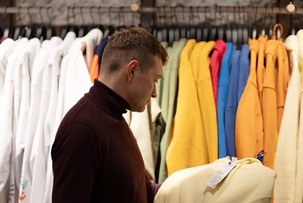 Mağazadaki renkli kıyafetler bölümünde bir adamın fotoğrafı.