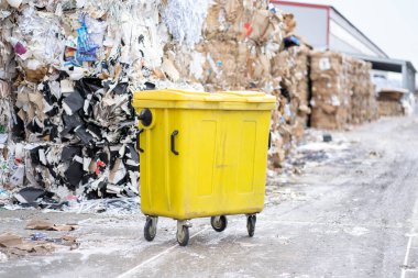 Arka planda bir sürü çöp olan sarı çöp kutusu. Atık ayıklama üretimi