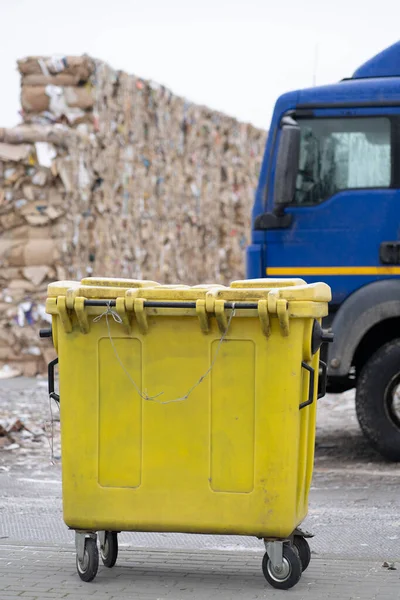 Arka planda sarı çöp kutusu var. Geri dönüşüm tesisinde öngörülen kağıt atığı yığını