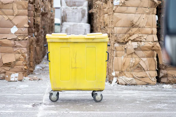 Büyük ambalajlı bir çöp kutusunun önündeki sarı çöp kutusunun fotoğrafı. Atık ayıklama üretimi.