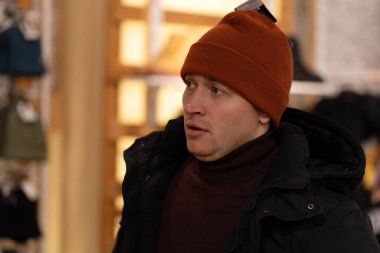 Kış şapkası seçen bir adamın fotoğrafı.