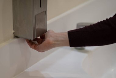 Ellerini yıkamak için sıvı sabun alan kazaklı bir adamın fotoğrafı. Temizlik ve hijyen..