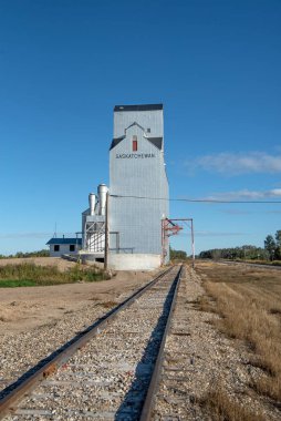 Kanada ovalarında Saskatchewan kırsalında bir demiryolunun yanındaki tahıl asansörleri.