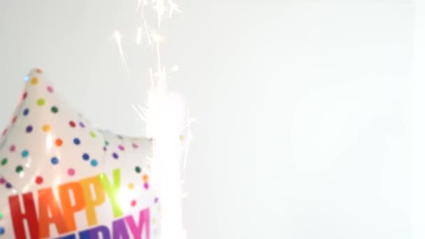 カラフルな言葉ハッピー誕生日は白い背景に前景に花火とヘリウム気球に書かれています — ストック動画