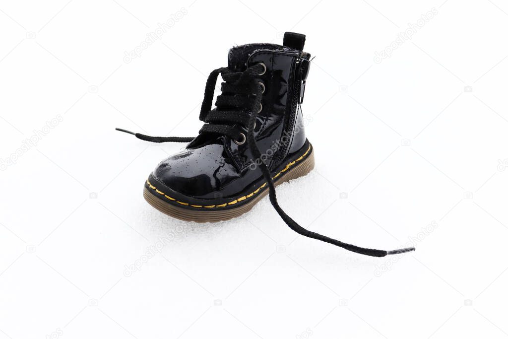 Winter wonderland with little black children's winter boot on snow