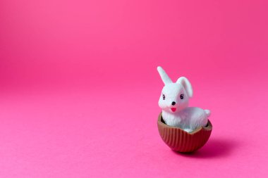 Paskalya Beyaz Tavşanı pembe arka planda çikolatalı yumurta kabuğu Paskalya Tatili Konsepti