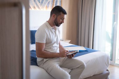  Çekici adam otel odasında oturuyor ve cep telefonuna bakıyor..