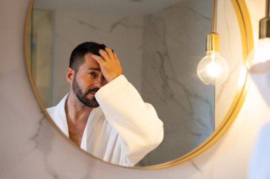  Bornozlu adam aynada kendine bakıyor..