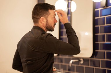 İşadamı banyo aynasında kendine bakıyor..