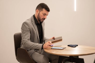 Tablet ve cep telefonuyla çalışan çekici genç işadamı.