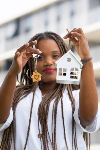  Minyatür bir anahtar zinciri ve minyatür bir anahtarla poz veren genç Latin kadın.