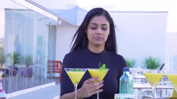 Молодая латинская женщина выпивает коктейль со своими друзьями. — стоковое видео