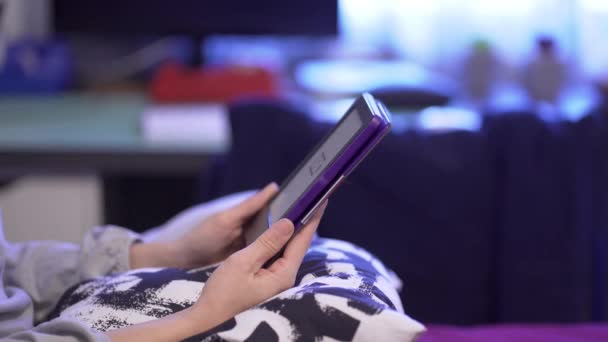 Junge schöne Kaukasierin sitzt zu Hause mit E-Book-Reader im Bett — Stockvideo