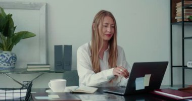 Mutlu, başarılı, sakin, sarışın patron, iş kadını yalnız çalışır. Laptop kullanır, modern ışık ofis masasında notlar alır..