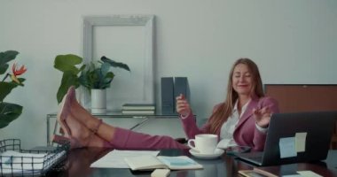 İş ve yaşam dengesi. Mutlu, başarılı, güzel bayan patron. Ofis masasında bacakları var. Akıllı telefon kullanıyor, rahatlıyor..