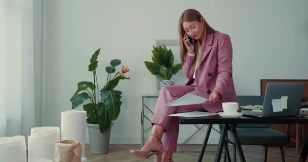 Happy successful boss business woman in pink suit talks over mobile phone sitting on office workplace table. — Stok Video